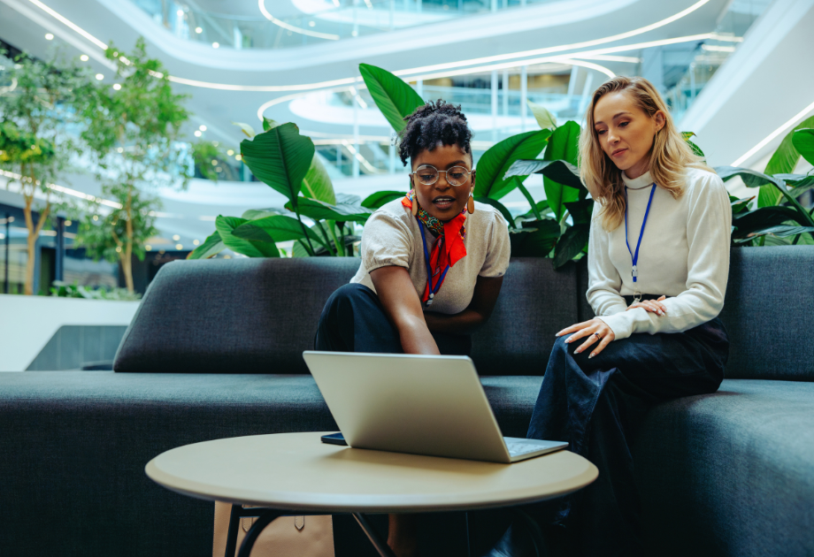 two business women sitting on a sofa looking at a laptop